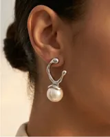 Aros colgantes de diseño orgánico en metal plateado con una perla central de acabado nacarado.