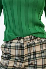 Pantalón de corte recto con estampado de cuadros escoceses en tonos beige, negro y verde. Presenta bolsillos delanteros funcionales y cierre frontal con botón.