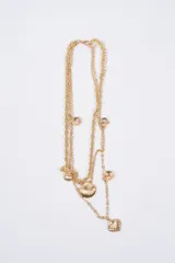 Collar multicapa de color dorado, compuesto por cadenas de diferentes texturas y adornado con múltiples dijes en forma de conchas marinas.