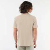 Remera de punto calado color beige, de manga corta, con cuello polo y escote en V sin botones.