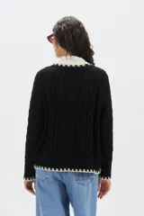 Sweater de punto de mohair color beige, con cuello redondo, mangas largas y detalles de terminación en color negro en el cuello, puños y ruedo.