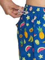 Short de baño azul con estampado tropical de frutas, cintura elástica con cordón ajustable gris y bolsillos laterales.