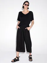 Pantalón negro tipo pescador, de corte amplio y tableado.