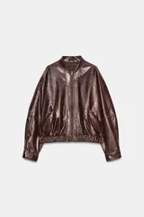 Chaqueta bomber de estilo oversize confeccionada en material efecto piel con acabado brillante. Presenta cuello redondo, cierre frontal con cremallera metálica, bolsillos laterales de vivo y bajo con elástico.
