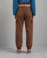 Pantalón cargo de jean color marrón con efecto desteñido, bolsillos laterales con solapa, cintura con presillas y puños elásticos en los tobillos.