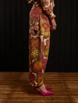 Pantalón de gabardina color marrón con estampado floral, corte carrot fit, tiro medio, estilo carpintero y detalles de botón de metal personalizado y parche trasero personalizado.