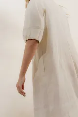 Vestido largo azul oscuro de lino 100% con escote en V, mangas abullonadas con elástico en el puño y pespunte en contraste. Presenta detalle de punto smock en el canesú y bolsillos laterales.