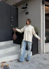 Buzo oversize color crema de tejido elastizado, cuello alto, puños ajustados y tajos laterales.