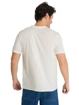 Remera de algodón color beige con cuello redondo y mangas cortas. Cuenta con un gran estampado gráfico frontal en tonos oscuros con la inscripción 'Power For' y 'Caterpillar', acompañado de una ilustración de maquinaria e infraestructura industrial.