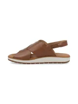 Sandalia de cuero color camel con tiras cruzadas en el empeine, tira trasera de ajuste y suela plana con plataforma dentada en tono blanco y marrón.