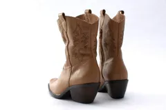 Botas de estilo western (texanas) de caña media, color blanco, confeccionadas en cuero. Presentan bordados decorativos en la caña y puntera cuadrada. Cuentan con cierre lateral y taco de altura media.