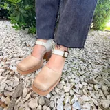 Sandalia de cuero modelo Berlin, con plataforma y taco ancho de madera, punta cuadrada y tira ajustable al tobillo con hebilla metálica.