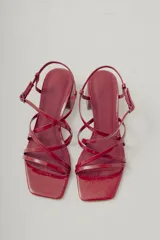Sandalia de tiras finas color rojo brillante, con puntera cuadrada y taco ancho de altura media. Posee tira ajustable con hebilla en el tobillo.