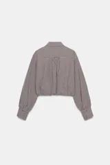 Camisa corta de manga larga con cuello solapa, confeccionada en tela con estampado de cuadros vichy en color bordó y blanco. Presenta un bolsillo delantero de plastrón, cierre frontal con botones y bajo abullonado con elástico interior.