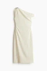 Vestido midi color crema con textura arrugada, de corte ajustado. Presenta un diseño asimétrico de un solo hombro, con tirante fino adornado con anillas metálicas doradas en un lado, y un corte ancho en el otro. Tiene frunces laterales que generan un efecto drapeado.