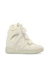 Zapatilla de caña alta, color blanco hueso, con cierre de tres tiras de velcro. Presenta recortes en gamuza y paneles acolchados en el lateral, con suela de goma gruesa.