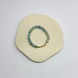 Pulsera de cuentas esféricas de piedra natural amazonita de 8 mm, con separadores de hilo en tono verde agua y cierre de mosquetón con baño de oro.
