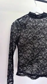 Top de encaje negro con cuello alto y mangas largas.