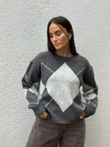 Sweater de punto con diseño de rombos en tonos gris oscuro y gris claro, de corte holgado, cuello redondo y manga larga.