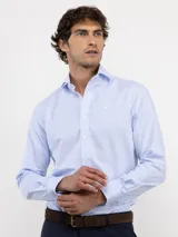 Camisa de manga larga con diseño de rayas verticales finas en color celeste y blanco. Presenta cuello clásico, cierre frontal con botones y logo bordado en el pecho.
