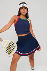 Conjunto deportivo compuesto por un top sin mangas de cuello redondo con detalles en contraste y una pollera tableada de tiro alto con franjas decorativas en el ruedo.