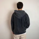 Campera con capucha y cierre frontal, confeccionada en tejido con efecto lavado desgastado. Presenta costuras decorativas horizontales en la parte superior del pecho y bolsillos laterales.