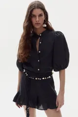 Short negro de lino 100% natural, de tiro medio-alto, con elástico interno en la cintura, bolsillos laterales y volados decorativos en el ruedo.
