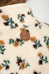 Campera de corderito con estampado floral en tonos tierra sobre base color crema. Presenta cuello redondo, cierre frontal con botones a presión y ribetes en color crema.