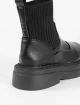 Botas negras de cuero sintético con caña elastizada y suela track.