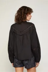 Camisa negra de manga larga estilo globo, justa al cuerpo con detalles de aberturas pequeñas que generan una trama en el pecho y en las mangas.