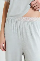Pijama de dos piezas en color gris melange, compuesto por una remera de manga corta con detalles de encaje en los bordes y un pantalón de corte recto con cintura elástica y detalle de encaje en la pretina.
