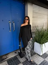 Conjunto de buzo asimétrico de manga larga con hombro descubierto y pantalón tiro alto de pierna ancha con estampado animal print tipo cebra, confeccionados en viscosa.