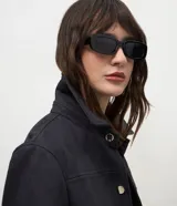 Chaqueta de corte recto confeccionada en suede sintético color marrón. Presenta cuello estilo camisa, cierre frontal con botones metálicos, mangas largas con puños ajustados y bolsillos embutidos.