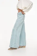 Jean wide leg de tiro medio color celeste claro, con doble pretina y detalles de costuras laterales con flecos deshilachados.