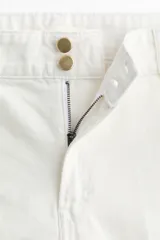 Pantalón de jean color crudo, de corte wide leg y tiro alto. Presenta cierre frontal con doble botón metálico y pliegues marcados en la parte delantera.