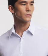 Camisa de vestir blanca de algodón con textura maquinetada, cuello camisero y mangas largas.