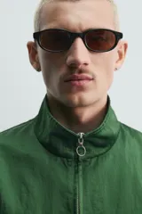 Campera verde oscuro de corte cropped y tejido técnico, con cuello alto, cierre frontal de cremallera con tirador circular, bolsillos ribeteados y puños y dobladillo elásticos.