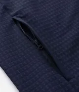 Chaqueta deportiva masculina de color azul marino, confeccionada en tejido técnico repelente al agua con acabado texturizado. Presenta cierre frontal con cremallera, capucha integrada y estampado de coordenadas en el pecho.
