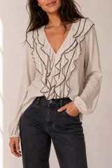 Blusa celeste de manga larga con escote en V y volados en cascada ribeteados en color oscuro. Cuenta con puños elásticos.
