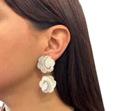 Aros colgantes con forma de flor hechos de nácar con detalles dorados.