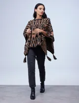 Poncho tejido con diseño tribal en blanco y negro, terminación con borlas.