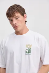 Remera oversize gris de algodón, de manga corta, con estampa en la espalda de formas botánicas abstractas y el logo de la marca.