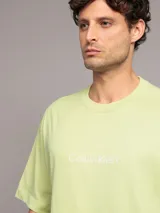 Remera verde claro de algodón con cuello redondo y logo de Calvin Klein estampado en el pecho.