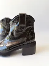 Botas texanas negras de cuero charol con caña baja, punta fina y tacón cuadrado.