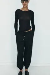 Pantalón de tiro medio con cintura elástica ajustable mediante cordones. Presenta bolsillos delanteros y bajos terminados en puño elástico con detalle de botón.