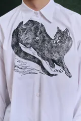 Camisa blanca de algodón con cuello clásico, manga larga con puños abotonados y estampado frontal de un animal similar a un zorro.