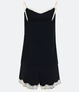 Conjunto de pijama negro, compuesto por un top de tirantes con encaje blanco en el escote y un short con encaje blanco en el ruedo.