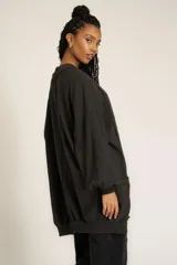 Cárdigan negro de tejido de punto con diseño holgado, cuello y puños acanalados, bolsillos laterales y mangas largas abullonadas.