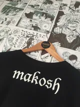 Remera negra de algodón con estampado de Levi Ackerman en estilo pop art y la palabra "ACKERMAN" en letras blancas. Estilo casual y urbano.