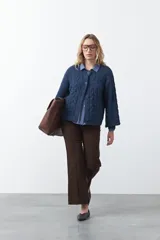 Cardigan de tejido de punto color marrón chocolate, con diseño de trenzas en el frente y mangas. Presenta cuello redondo, cierre frontal con botones al tono y puños acanalados.
